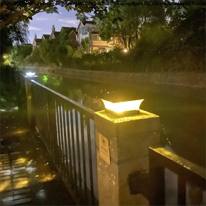 Applique luminaire exterieur haloria avec lumière led chaude dorée et design moderne montée sur pilier en pierre