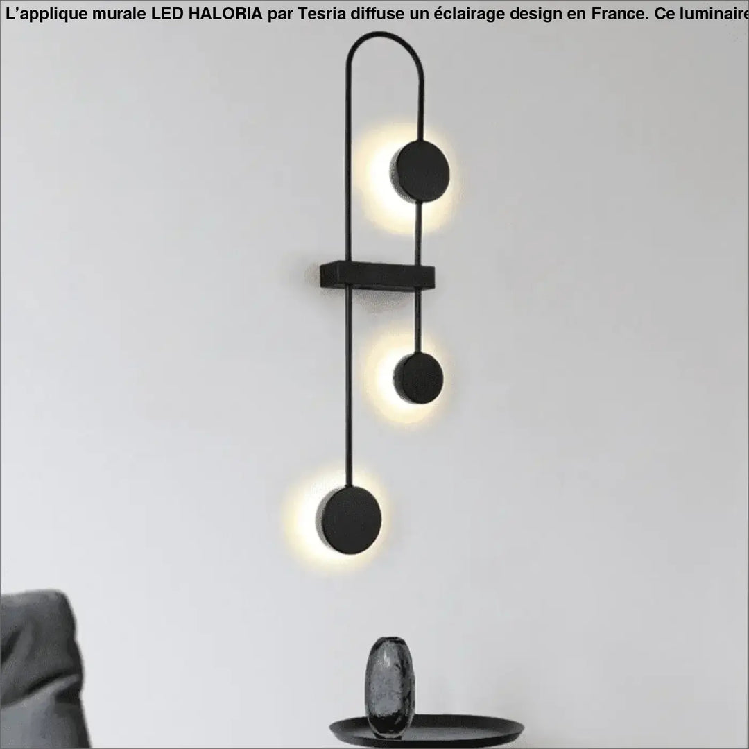 Applique mural led haloria noir minimaliste avec trois cercles lumineux verticaux émettant une lueur chaude