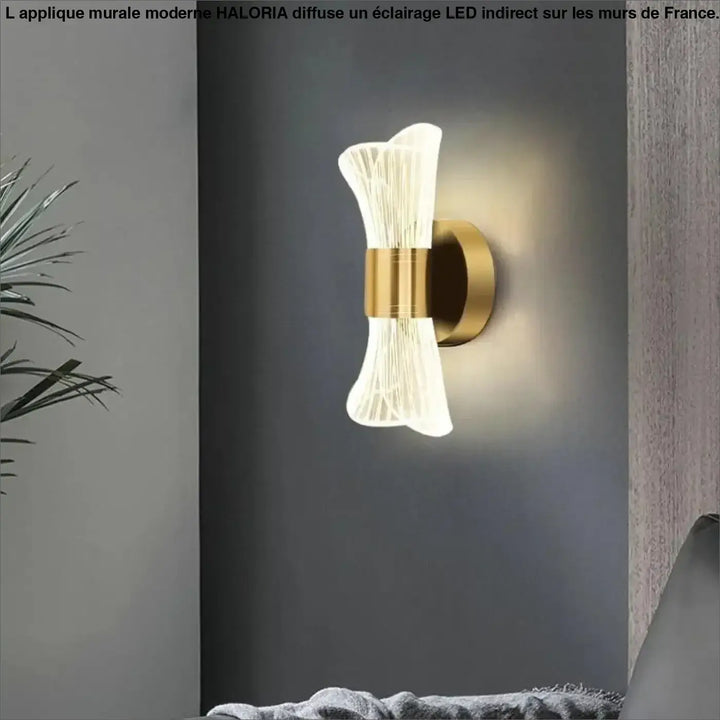 Applique mural moderne gold ton avec abat-jour en verre translucide strié émettant une lumière chaude haloria
