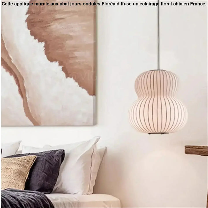 Une lampe à pendentif beige et côtelée, au design en forme de gourde, est suspendue à un fin cordon noir.