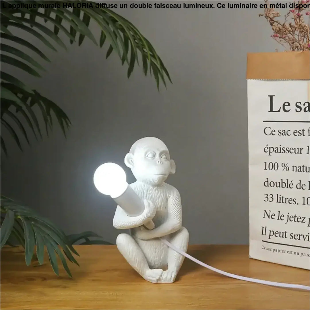 Lampe de table zaboo en céramique blanche avec singe assis sculptural tenant une ampoule lumineuse