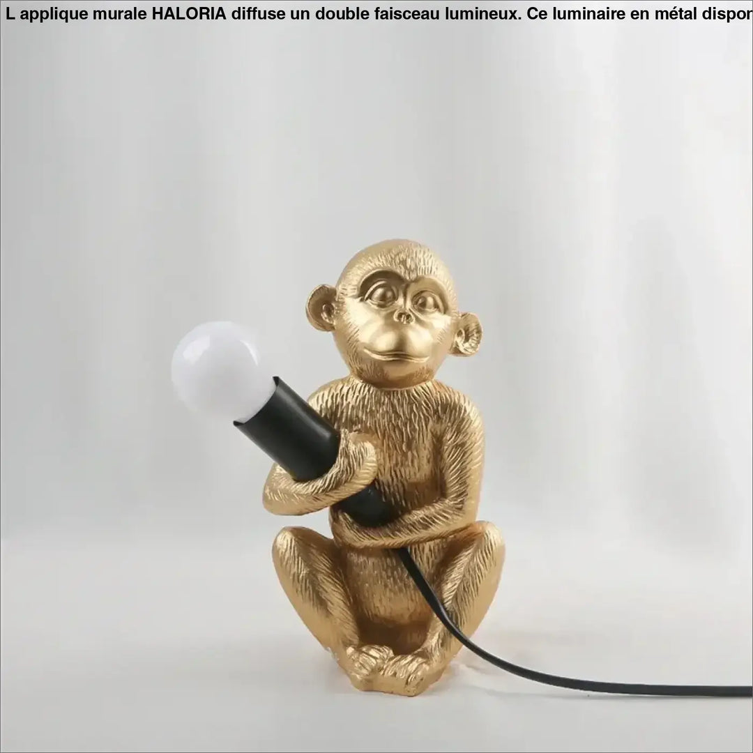 Lampe de table zaboo singe assis en métal texturé doré tenant une ampoule à poignée noire sculpturale singe assis