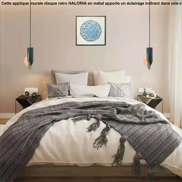 Une applique murale disque rétro avec une couverture grise en tricot et des pompons posée sur un lit