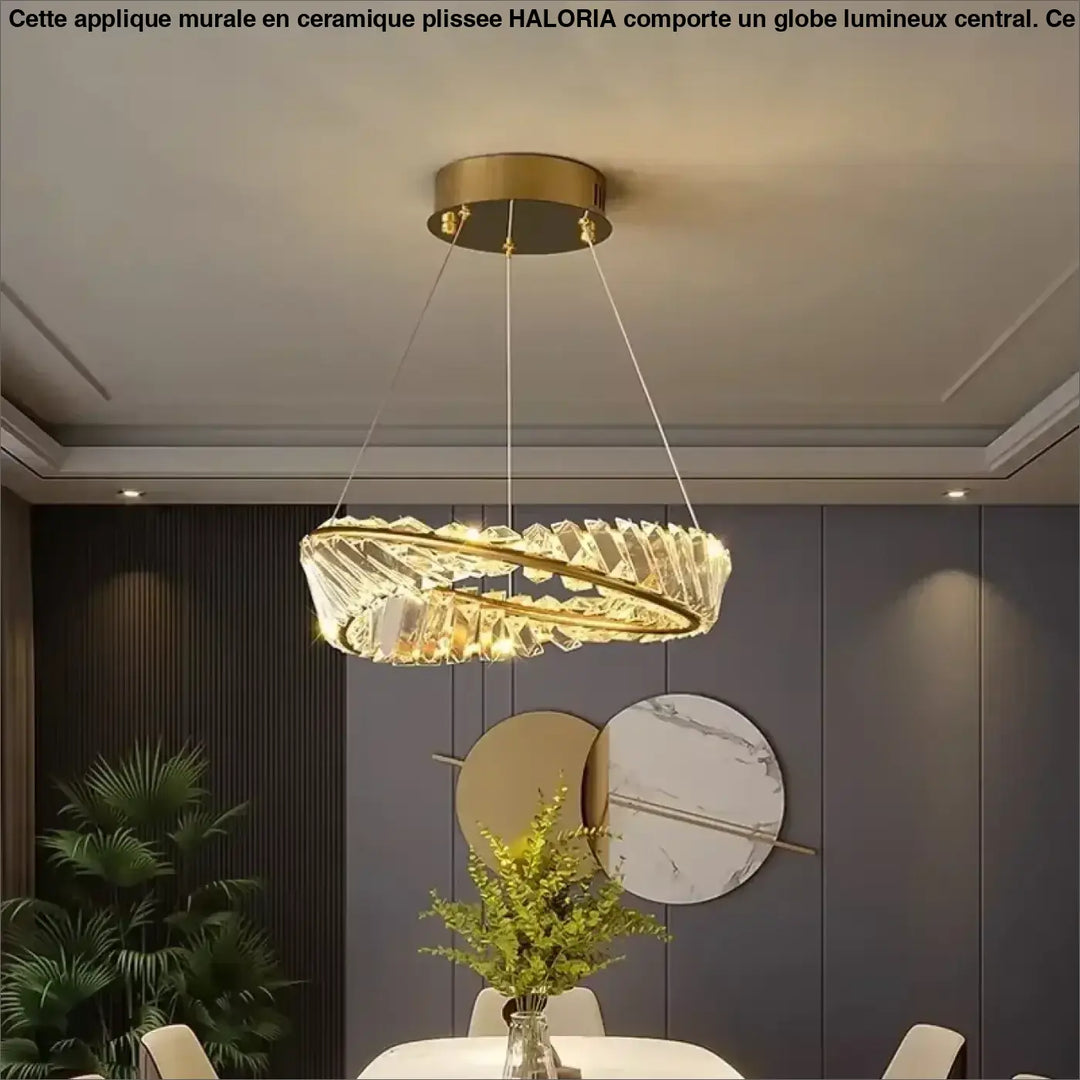 Un lustre moderne et circulaire, avec un cadre métallique aux tons dorés et des éléments transparents de type cristallin disposés en anneaux concentriques.