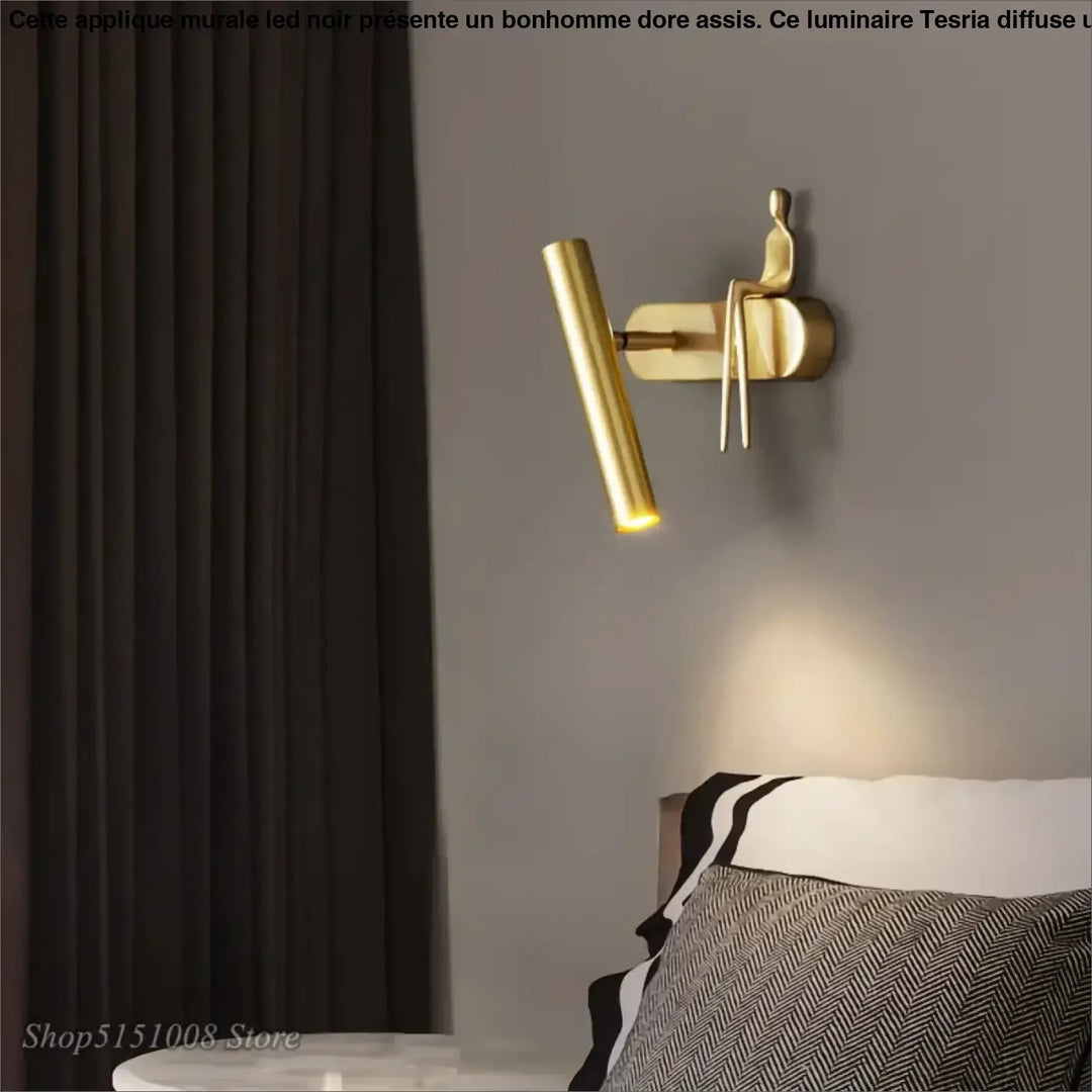 Applique murale LED noir avec un bonhomme doré assis

