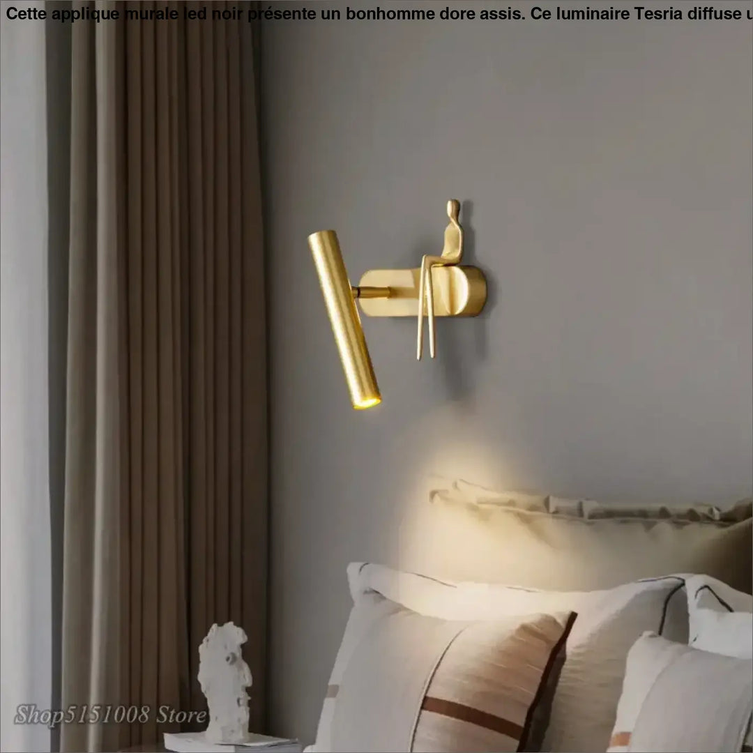 Applique murale LED noir avec un bonhomme doré assis

