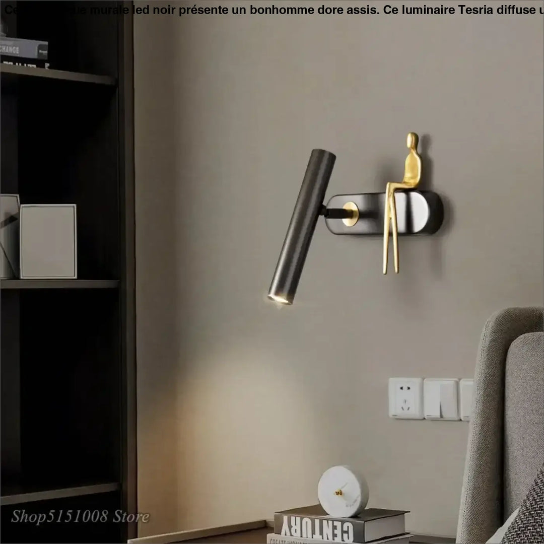 Applique murale LED noir avec un bonhomme doré assis

