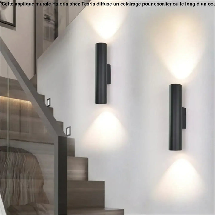 Applique murale haloria noire cylindrique en métal design moderne diffusant une lumière chaude autour d’un miroir ou long d’un couloir
