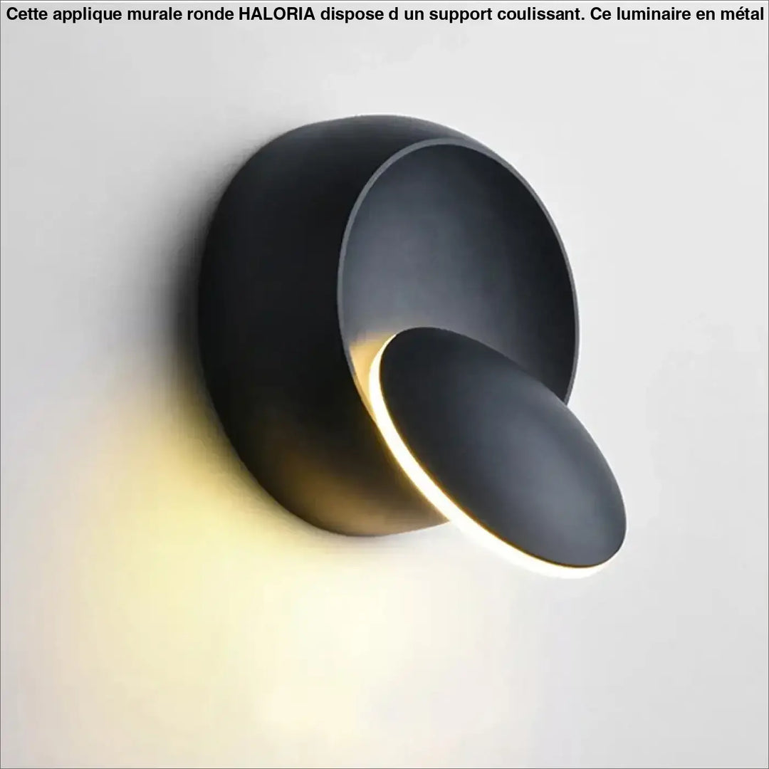 Applique murale ronde haloria en métal noir mat avec design sculptural et éclairage d’ambiance chaleureux