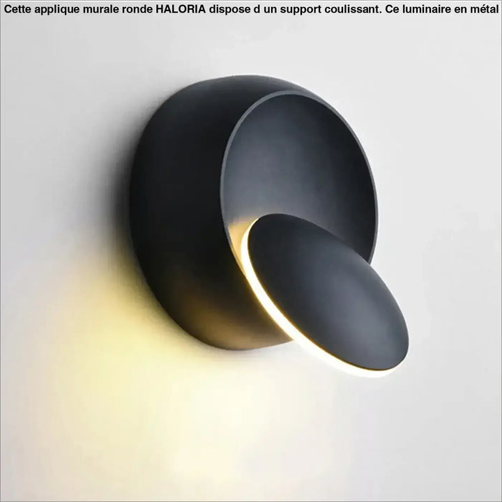 Applique murale ronde haloria en métal noir mat avec design sculptural et éclairage d’ambiance chaleureux