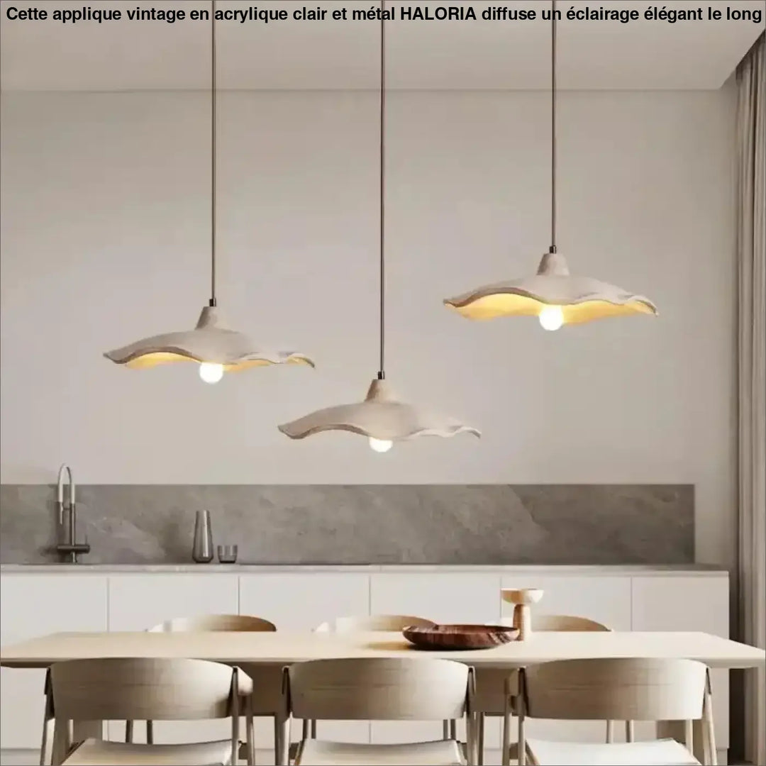 Trois appliques vintage en acrylique clair avec base en metal et abat-jours ocre suspendues au-dessus d’une table à manger moderne