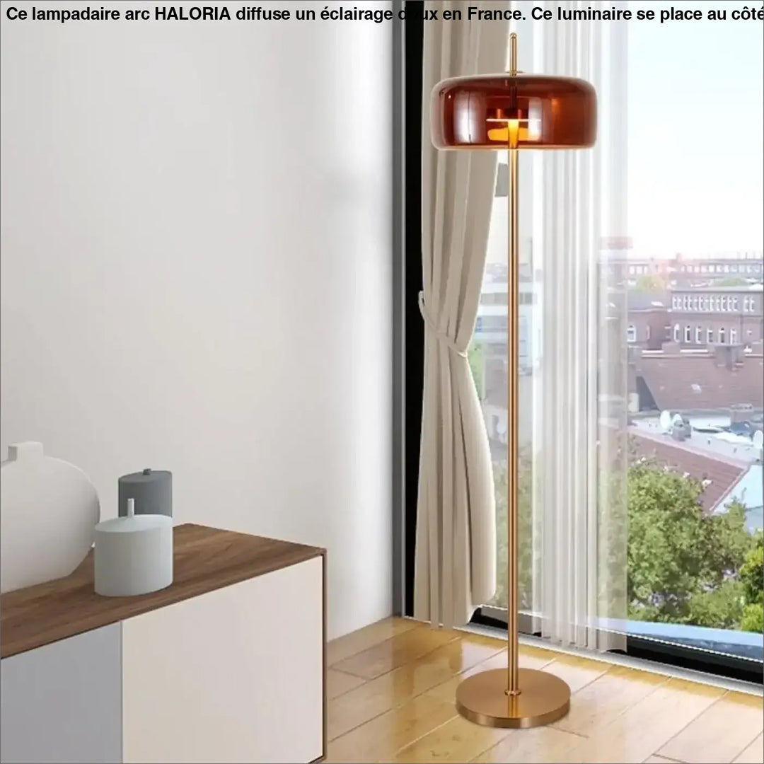 Lampadaire arc grand en verre ambré avec finition laiton et design minimaliste côté d’un canapé haloria