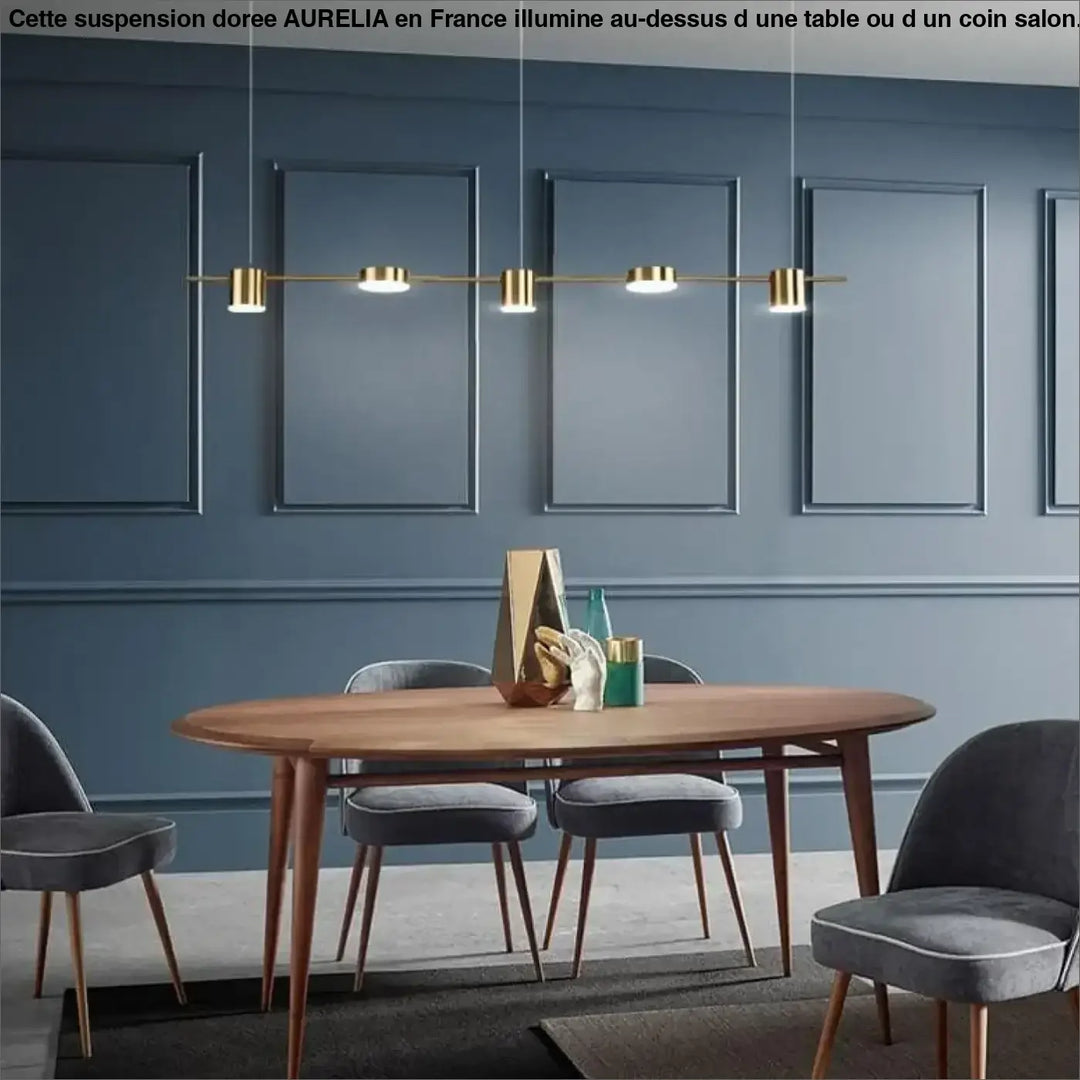 Grande suspension doree aurelia en métal doré moderne avec quatre ampoules cylindriques au-dessus d’une table en bois