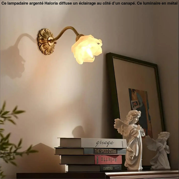 Antique lampadaire argente en laiton avec un abat-jour en verre en forme de rose translucide côté d’un canapé