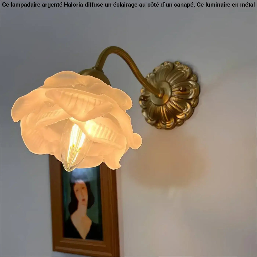 Lampadaire argente en laiton avec abat-jour en verre dépoli en forme de rose côté d’un canapé