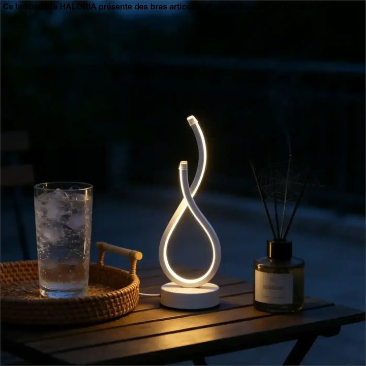 Lampe de table infinia blanche à boucle lumineuse moderne avec silhouette sculpturale posée sur table en bois