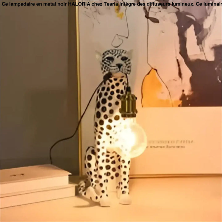 Lampe de table felina en céramique blanche en forme de chat tacheté avec ampoule suspendue visible pour table design léopard