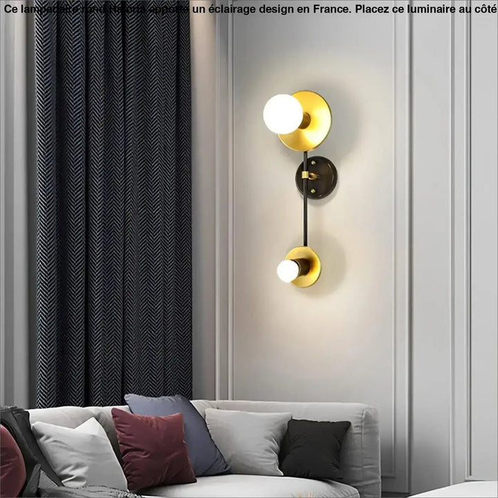 Lampadaire rond sur pied haloria en métal noir avec une applique murale dorée à deux globes côté d’un canapé