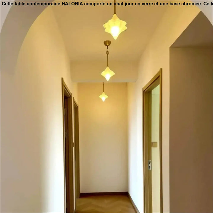 Trois suspensions luminaires petales en verre transparent aux tons chauds offrent un éclairage doux dans un couloir