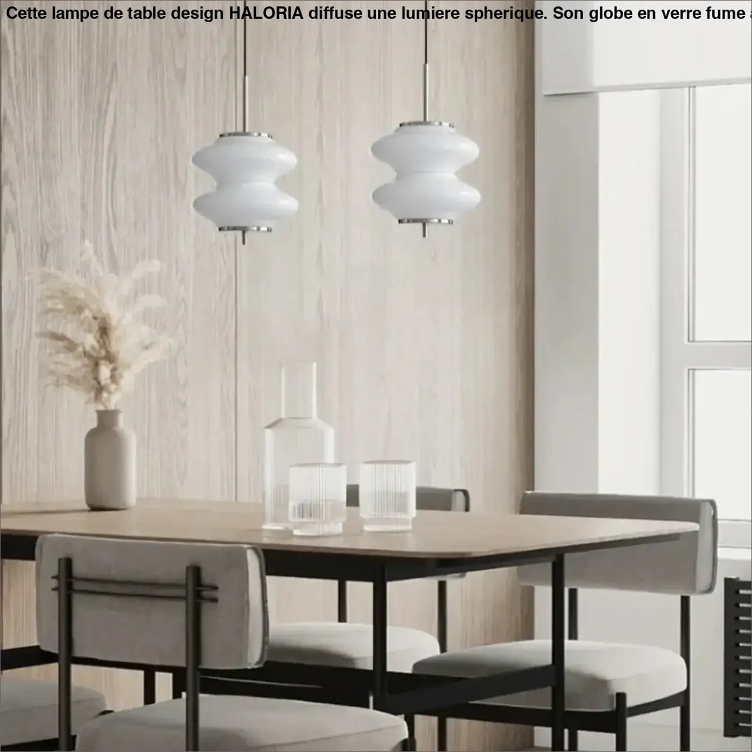 Deux suspensions luminaires en verre blanc en formes arrondies avec fixations métalliques au-dessus d’une table à manger