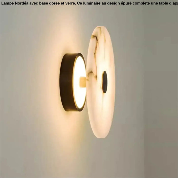 Applique murale moderne moonya avec un disque en marbre beige à veines fines et un support noir émettant une lumière douce