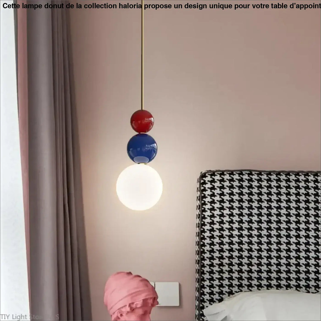 Suspension luminaire moderne resinia avec trois globes empilés rouge bleu blanc suspendus sur cordon doré au-dessus dune tête de lit pied-de-poule
