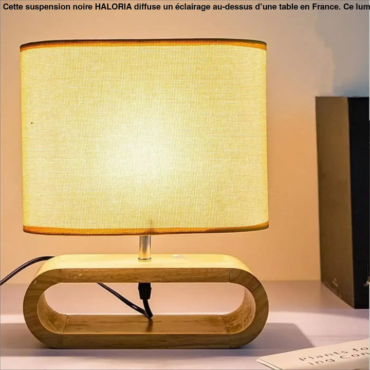 Lampe suspendue noir avec abat-jour rectangulaire en tissu texturé chaud sur pied en bois clair avec découpe ovale au-dessus d’un coin salon