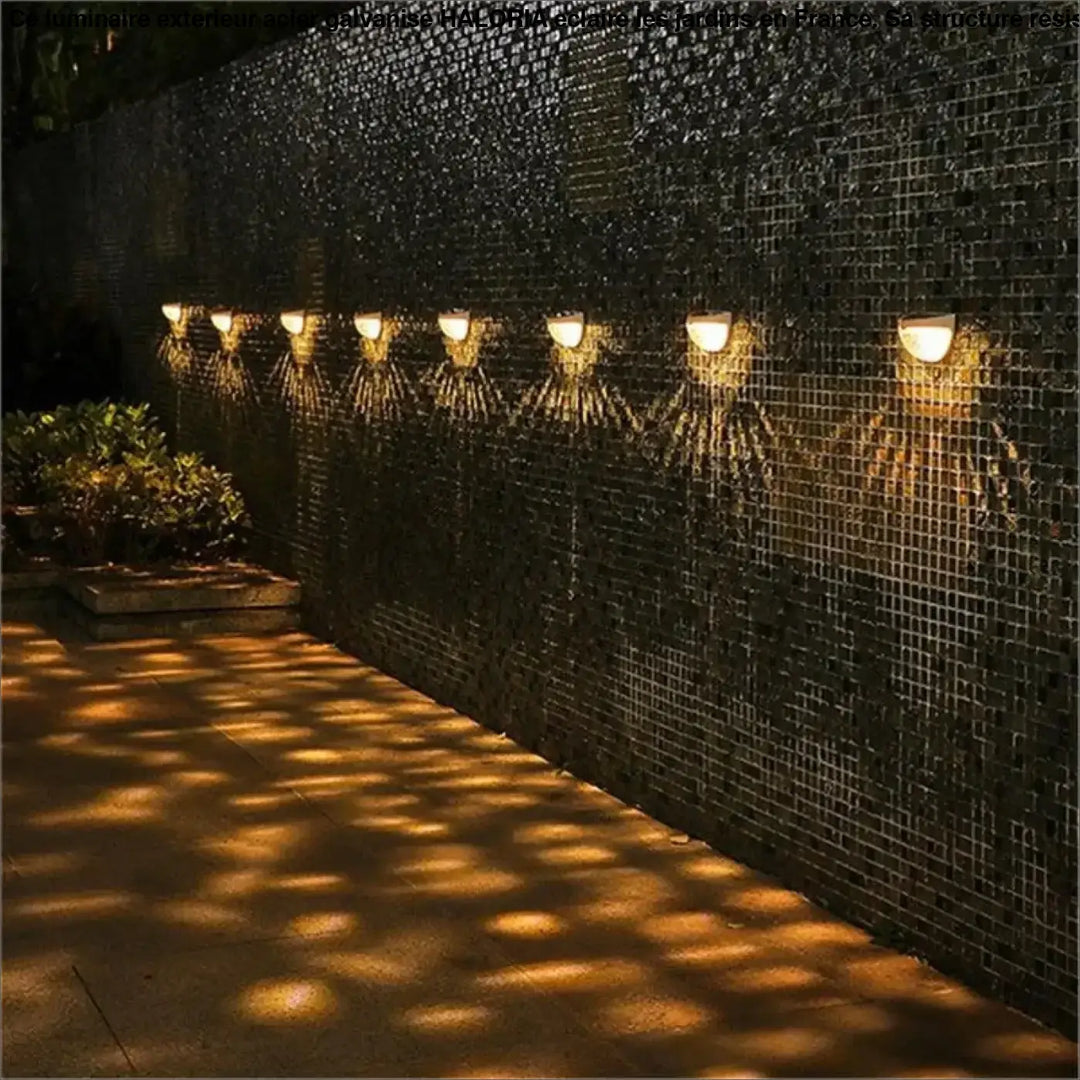 Luminaire exterieur acier galvanise haloria éclairant un mur en mosaïque avec des lumières encastrées ton chaud moderne