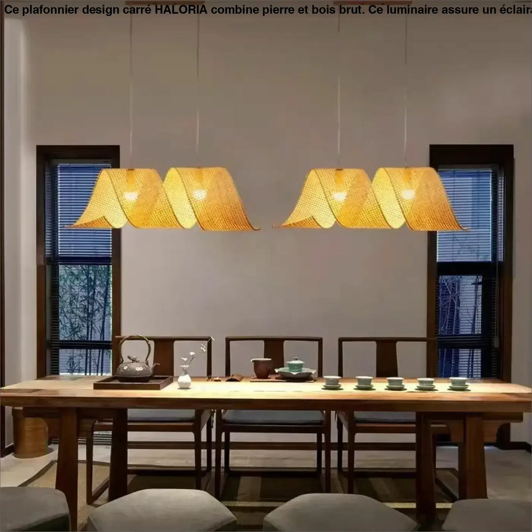 Plafonnier design carre en pierre et bois brut avec quatre suspensions en bambou tressé doré au-dessus de la table à manger