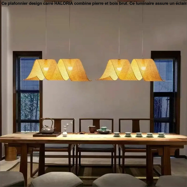 Plafonnier design carre en pierre et bois brut avec quatre suspensions en bambou tressé doré au-dessus de la table à manger