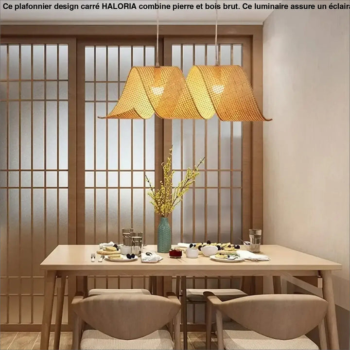 Plafonnier design carre en pierre et bois brut avec suspensions en bambou tissé aux tons chauds au-dessus d’une table à manger
