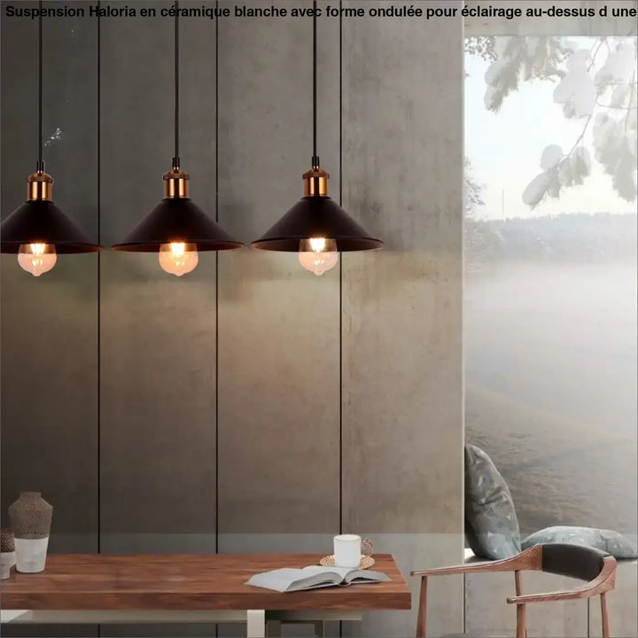 Trois suspensions luminaire ceramique blanc à forme ondulée avec accents en laiton suspendues au-dessus d’une table en bois
