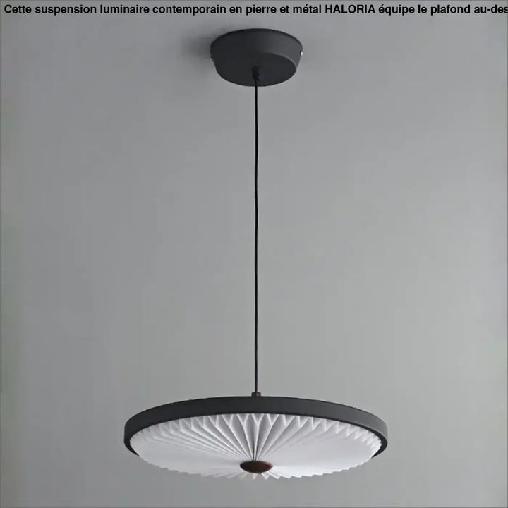Suspension luminaire contemporain haloria en pierre et metal noir avec diffuseur plissé blanc et accent en bois au-dessus d’une table