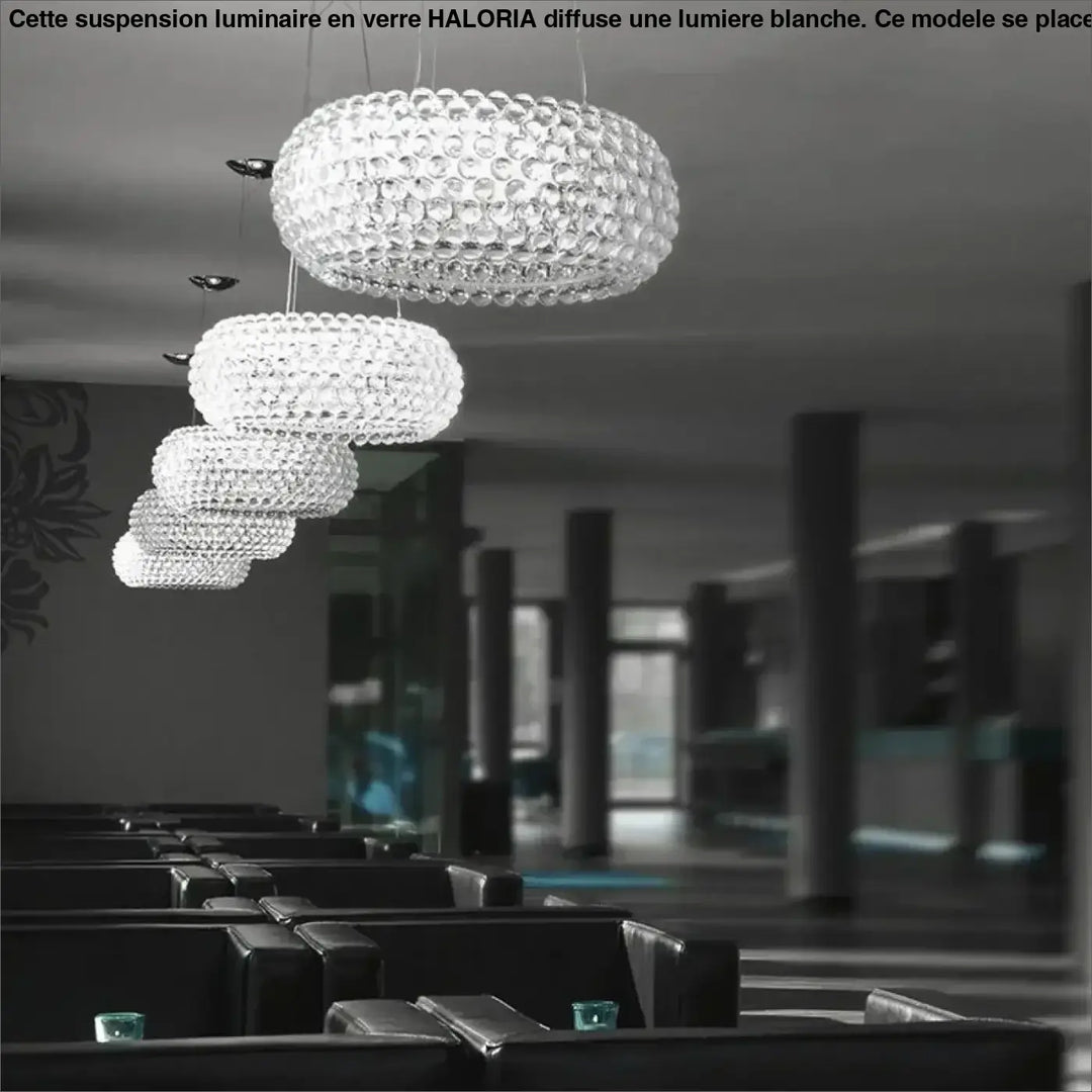 Suspension luminaire en verre facetté clair avec lumiere blanche au-dessus d’une table design sphérique moderne haloria