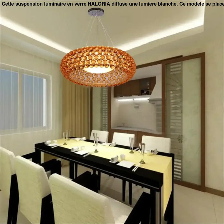 Suspension luminaire en verre orange avec lumière blanche au-dessus d’une table design circulaire moderne haloria