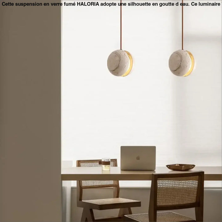 Suspension luminaire kreto avec abat-jours en béton texturé et accents halo doré au-dessus d’une table en bois travertin aux lignes