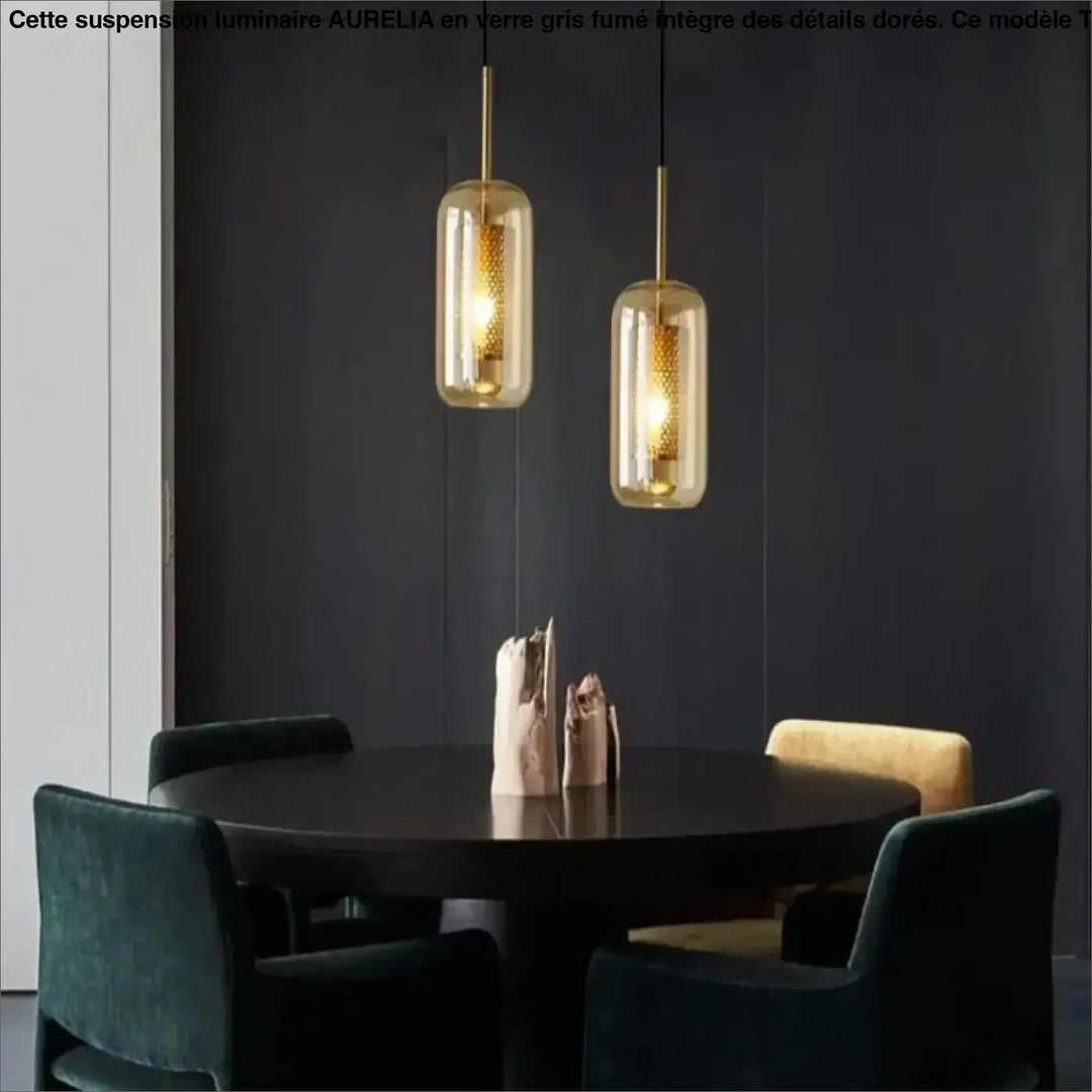 Deux suspension luminaires eloria dorées avec verre transparent aux nuances ambrées au-dessus d’une table en bois foncé