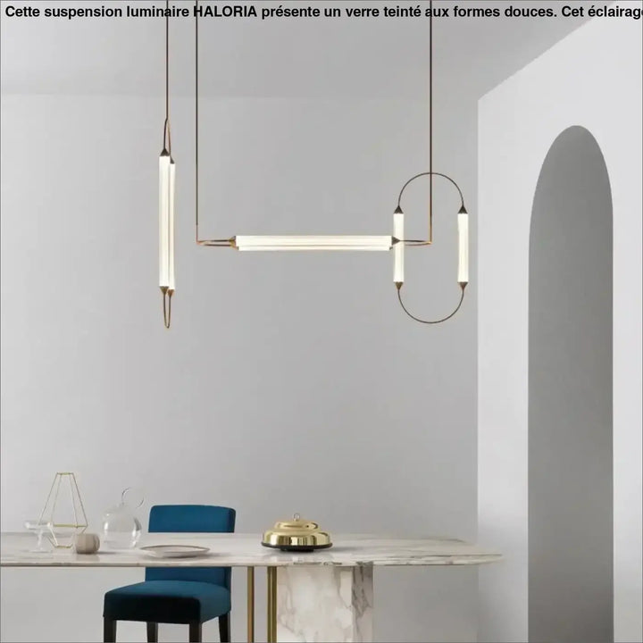 Suspension luminaire orsen avec sources lumineuses en tube de verre dépoli et cadre en laiton seul couleur au-dessus d’une table en marbre