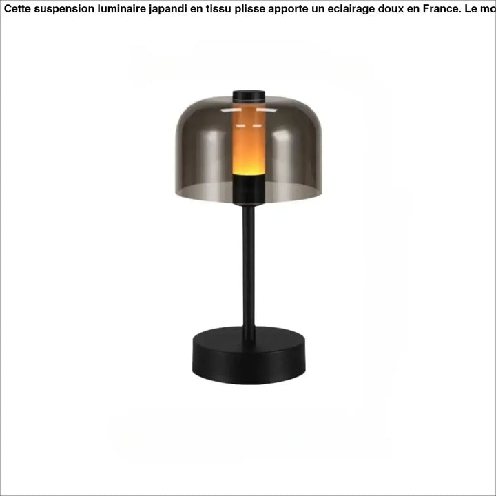 Lampe de table cristo en métal noir avec abat-jour en verre fumé diffusant une lumière orange chaleureuse idéale comme veilleuse
