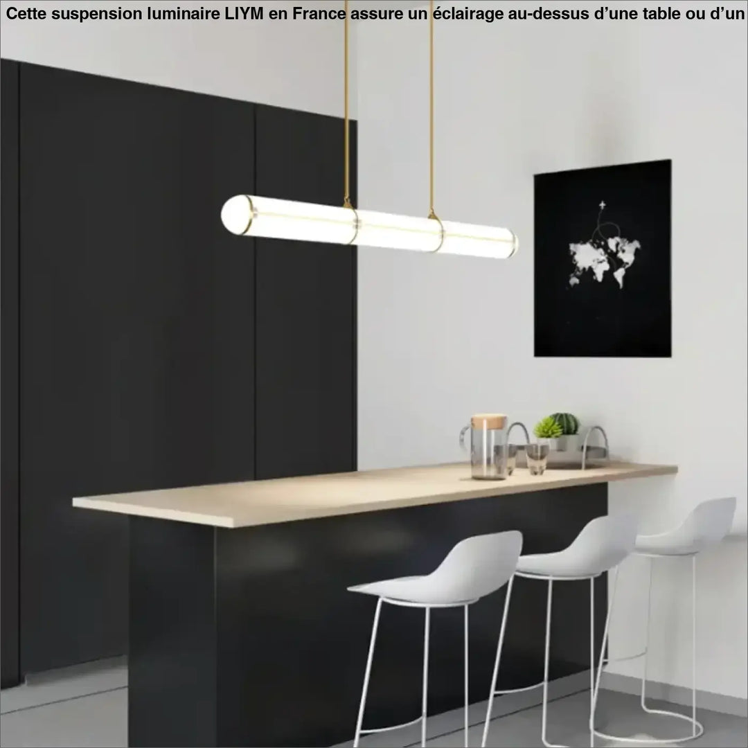 Suspension luminaire liym cylindrique moderne avec corps en verre blanc et suspension métal doré au-dessus d’une table