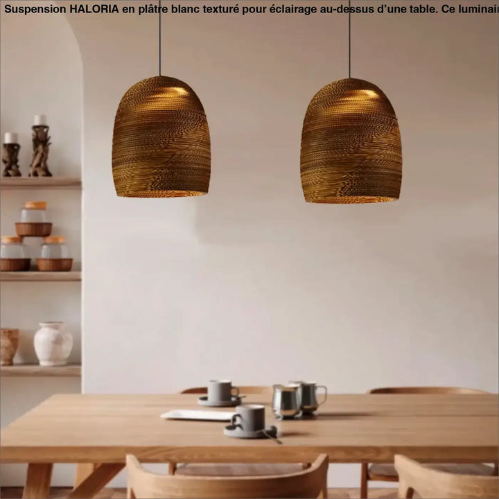 Deux luminaires modernes en plâtre blanc à texture dorée suspendus au-dessus d’une table en bois