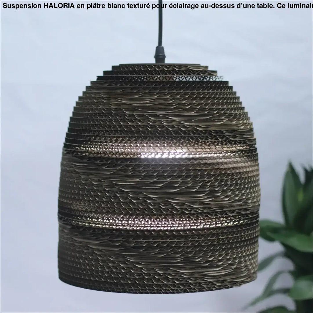 Suspension luminaire moderne en platre texture blanc au-dessus d’une table avec abat-jour en carton ondulé bronze ajouré