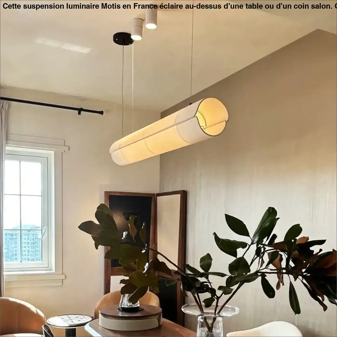 Suspension luminaire motis cylindrique avec abat-jour tissu blanc diffusant une lumière chaude au-dessus d’une table