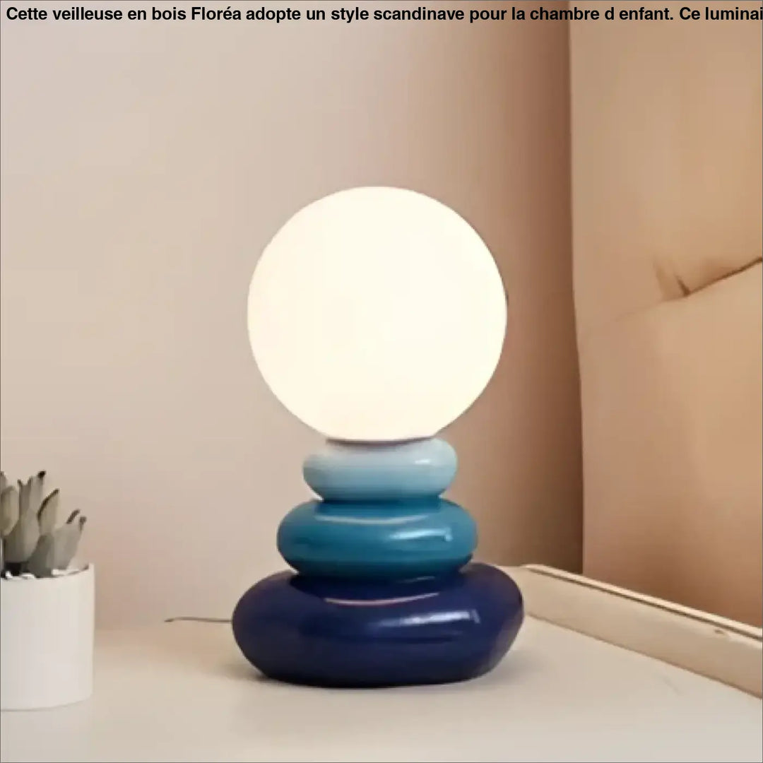 Lampe de chevet hestia avec design galets empilés et base circulaire bleue surmontée dune sphère lumineuse blanche