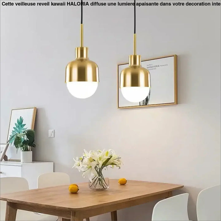 Deux suspensions luminaires avec finition dorée et abat-jours en verre dépoli au-dessus d’une table en bois