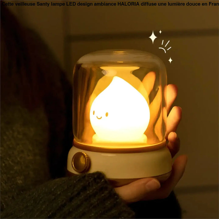 Une veilleuse santy lampe led design avec une créature jaune lumineuse sous une cloche en verre sur socle crème